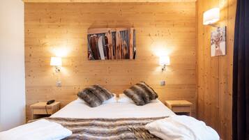 Una habitación con paneles de madera, una cama, dos lámparas de noche, un cuadro en la pared y un teléfono en la mesita de noche.
