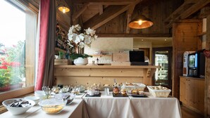 A dining area with tables set for a meal, a variety of dishes, and a kitchen in the background. - La Ferme du Lac (Thyez)