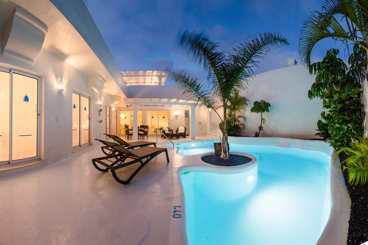 A pool area with lounge chairs, a small pool, and a covered seating area.