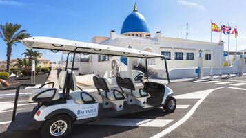 A golf cart with a sign reading "Bahiazul" parked in front of a building with a blue dome and flags.