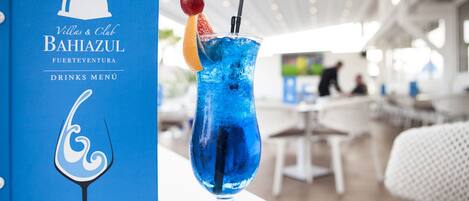 A drinks menu at a Bahiazul restaurant with a blue cocktail and a decorative fruit garnish.