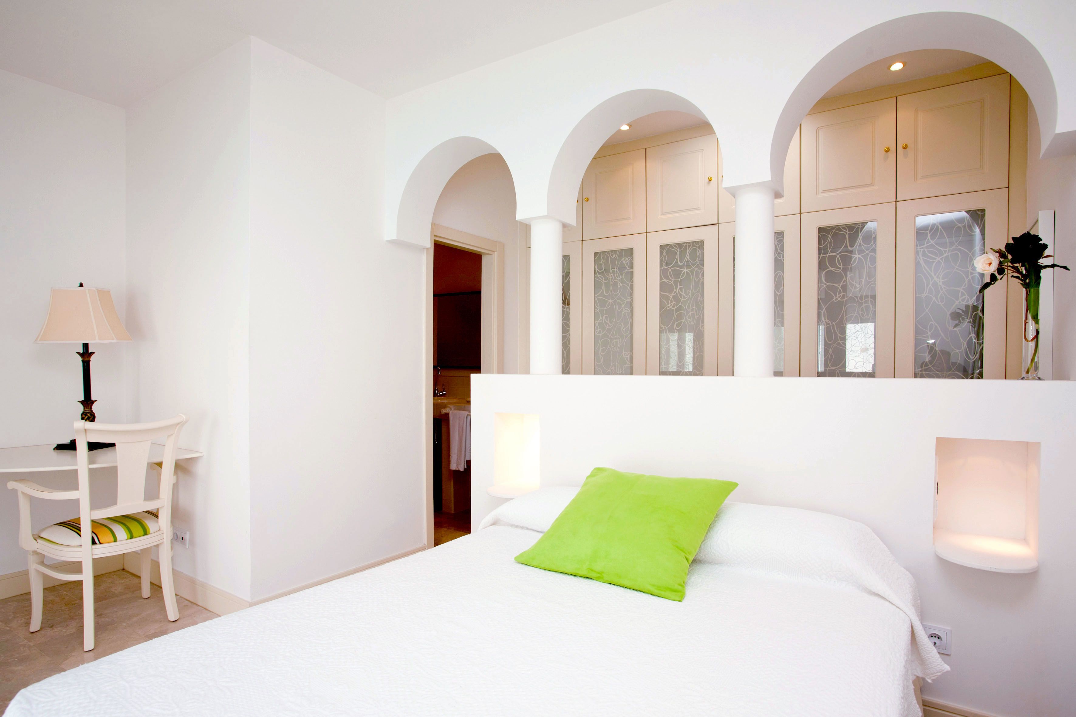 Habitación de hotel con cama, escritorio y silla. Hay una ventana con vistas al exterior.