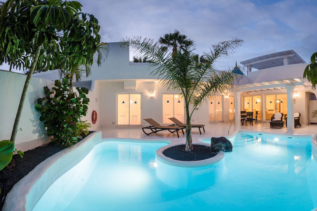 A modern outdoor pool area with lounge chairs and a dining area.