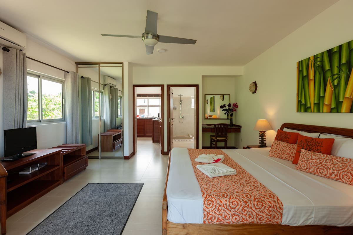 A hotel room with a bed, TV, desk, and a bathroom visible through an open door.