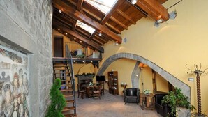 Un interior espacioso con chimenea de piedra, una escalera de madera y una zona de estar acogedora.