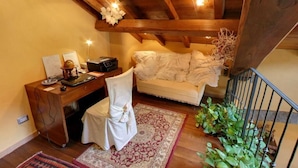 Una habitación acogedora con un escritorio de madera, una silla, un sofá y una escalera.