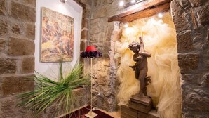 Un muro de piedra con un mural, una estatua y una lámpara roja.