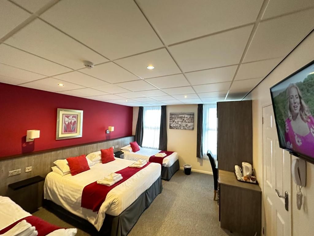 A hotel room with two beds, a television, a desk, and a window.