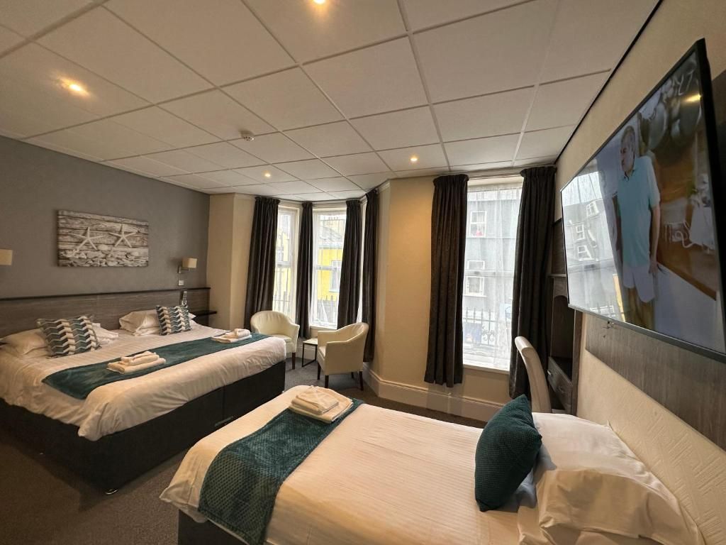 A hotel room with two beds, a desk, and a chair.