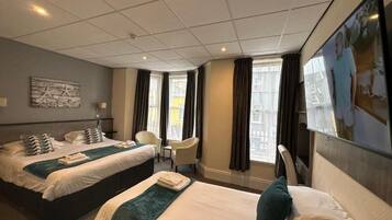 A hotel room with two beds, a desk, and a chair.