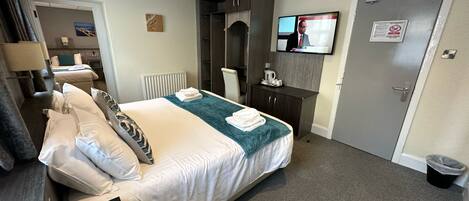 Una habitación de hotel con una cama grande, un escritorio, una silla, un televisor y una puerta con un letrero.