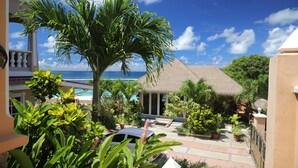 A tropical resort with a pool, thatched-roof building, and lush greenery. - Au Fond De Mer View (Mahé Island)