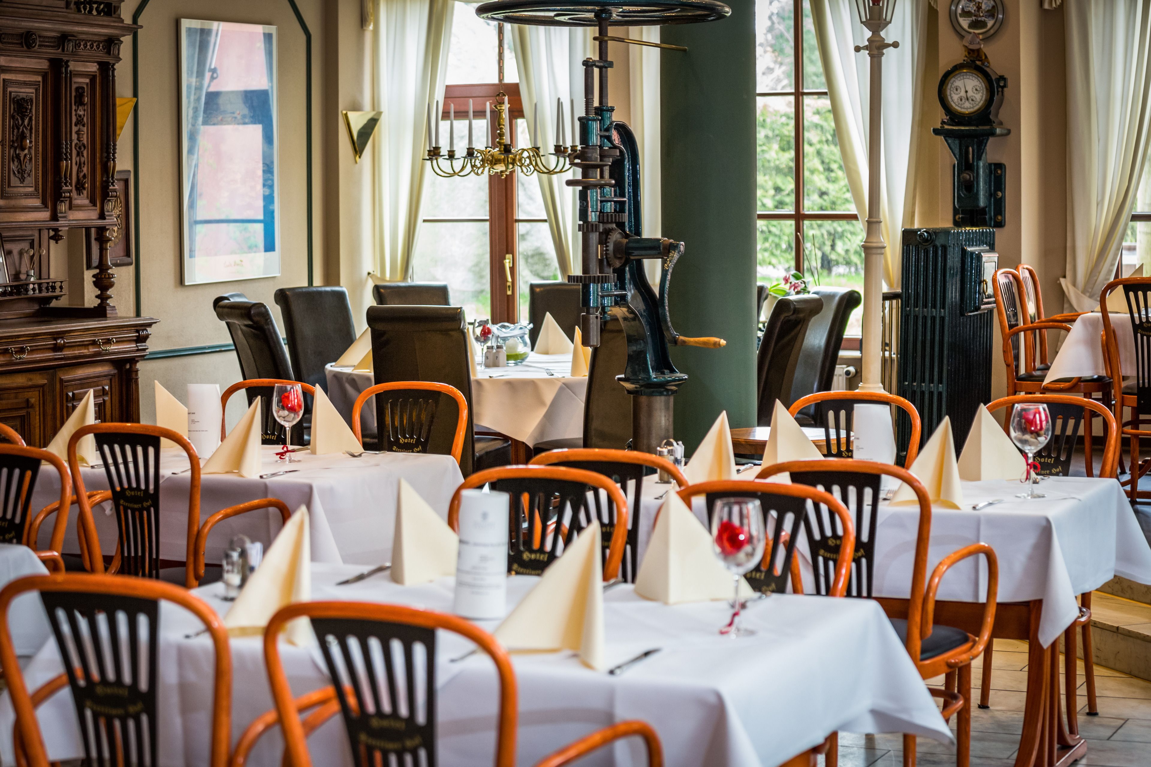 A dining area with tables set for service, chairs, and a vintage clock on the wall.