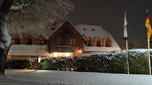 Un edificio cubierto de nieve con un estilo arquitectónico tradicional, que destaca por una torre central imponente y numerosas ventanas.