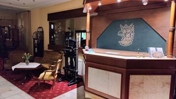 A reception area with a wooden reception desk, a sign reading "Rezeption," and a large mirror above the desk.