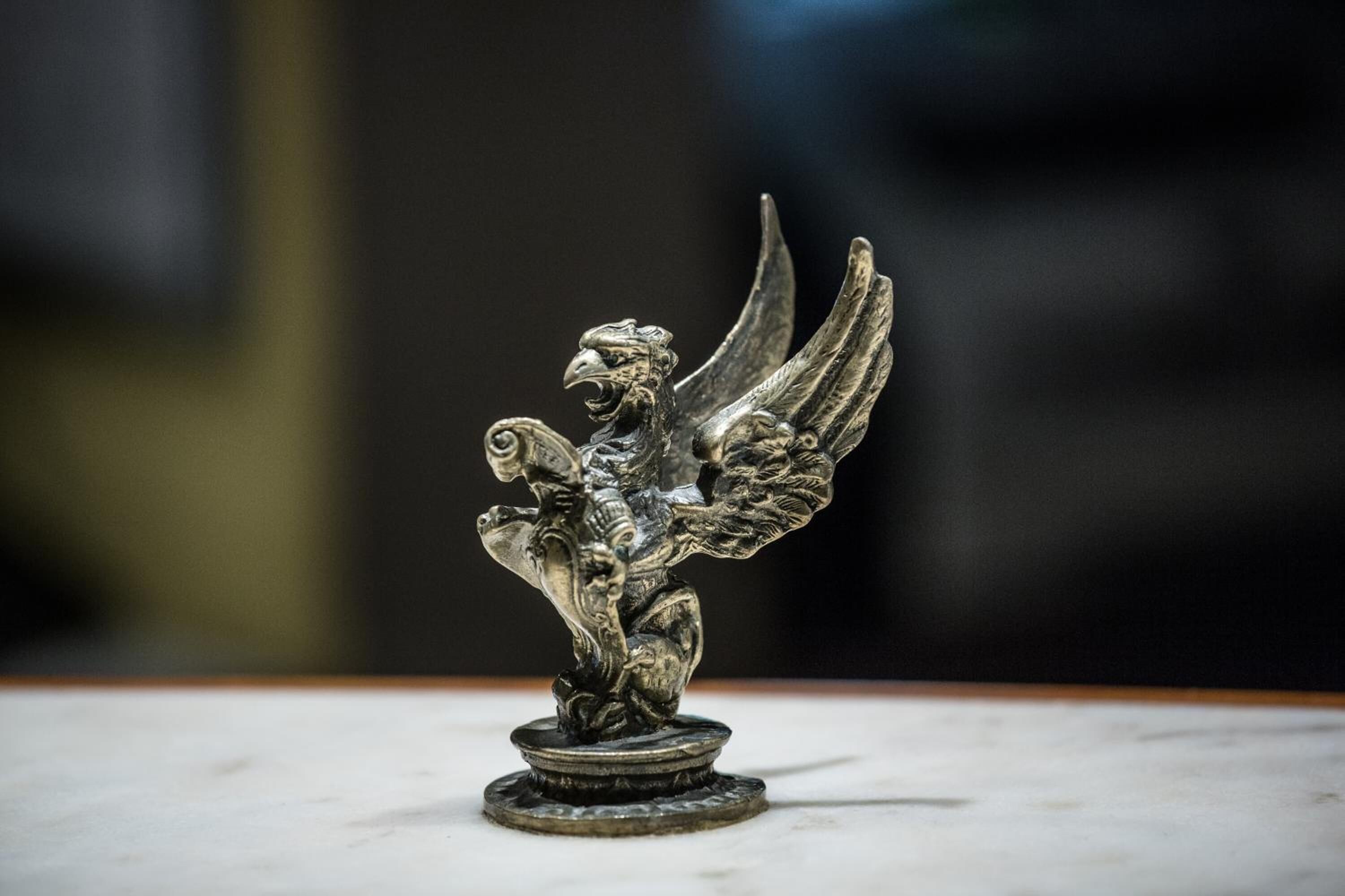 A metallic sculpture of a winged figure on a pedestal.