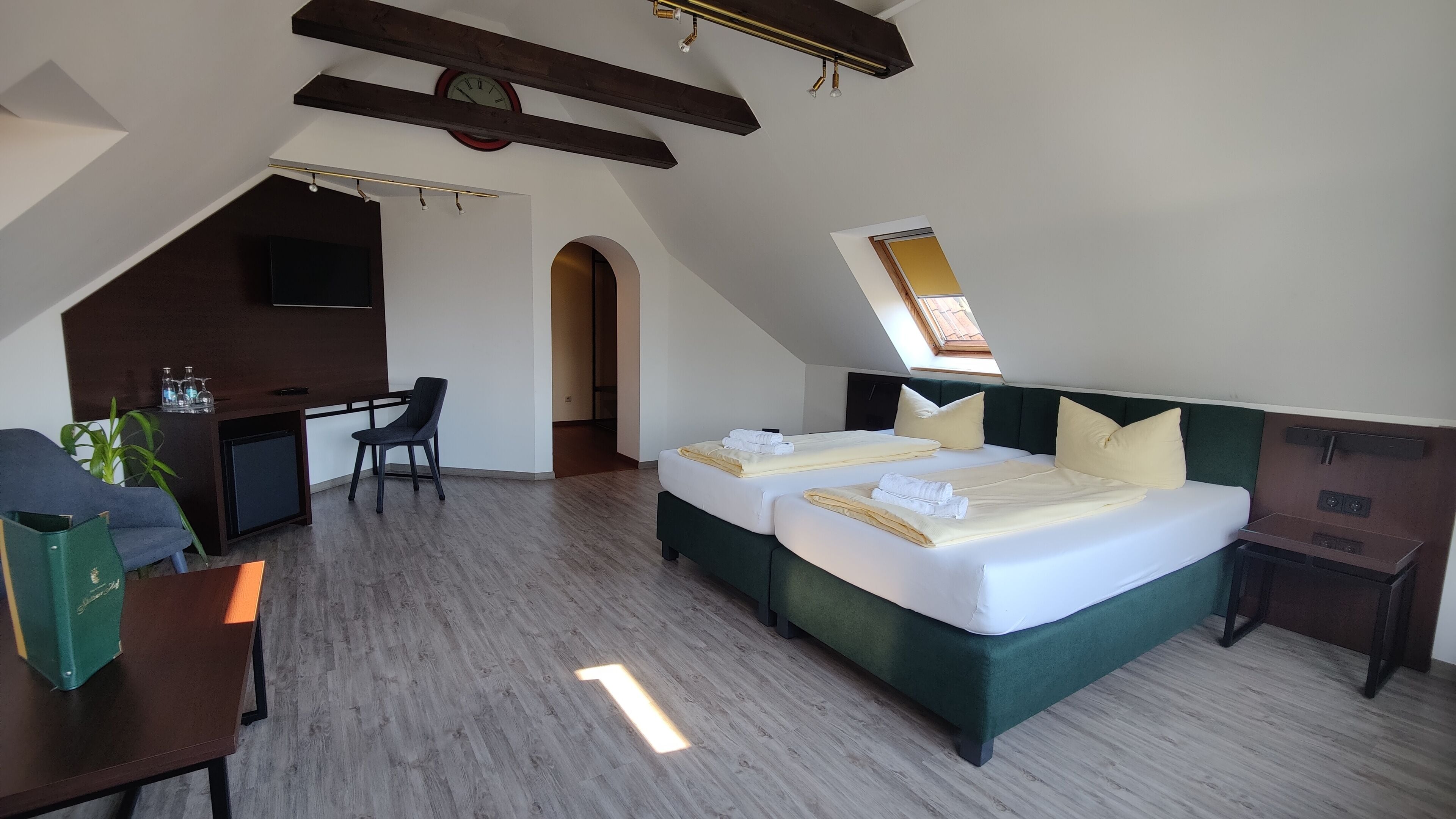 A hotel room with a large bed, a desk, and a chair.