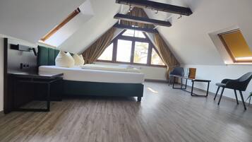 A modern bedroom with a bed, a desk, and a chair. There are large windows and a sloped ceiling.