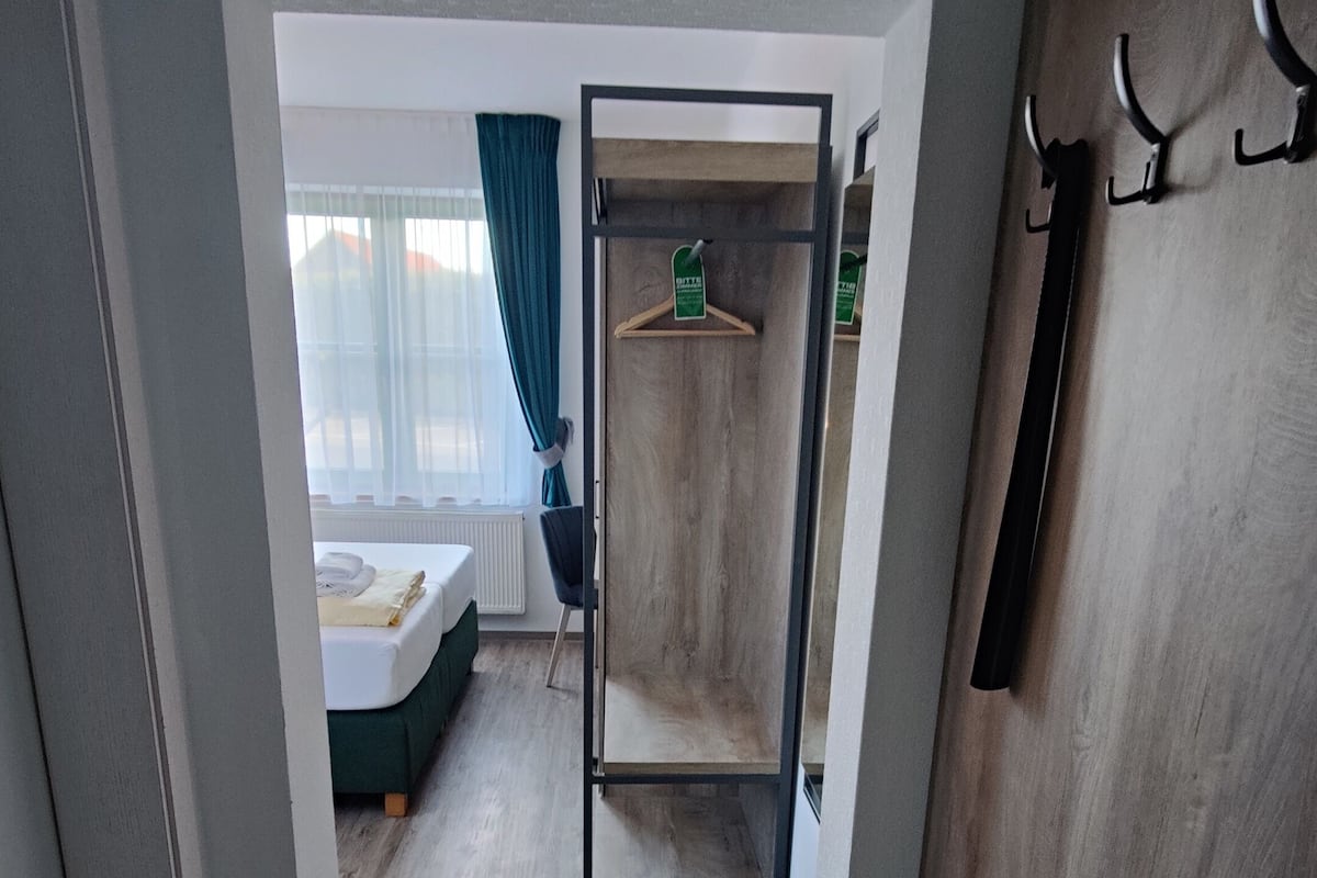 Una habitación con un armario de madera, un perchero y una cama con cabecera azul.