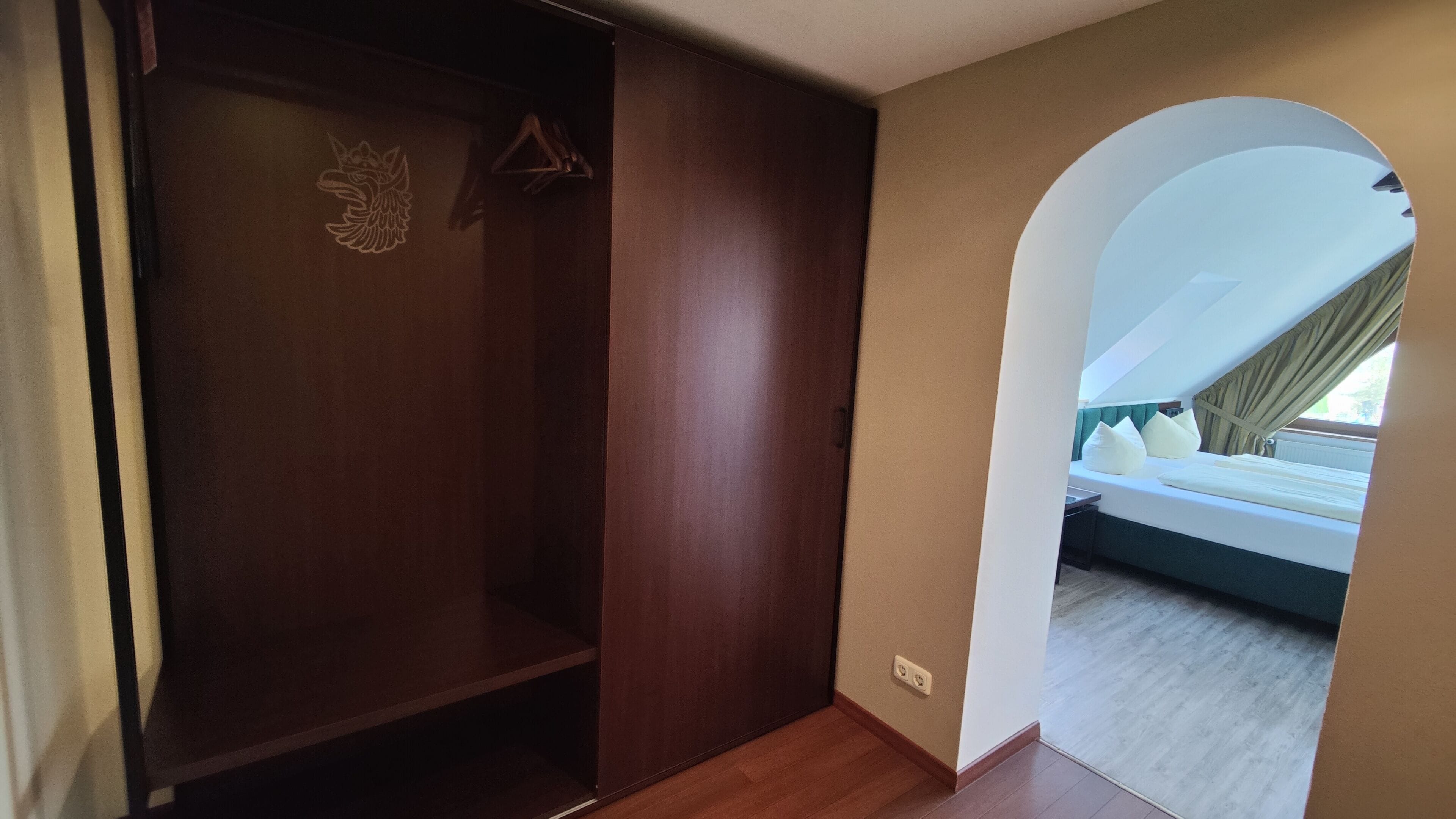 Una habitación con armario, cama y vistas a través de un arco.