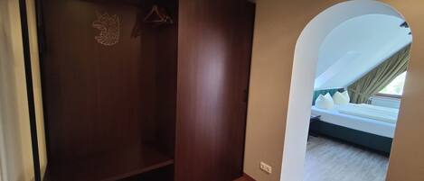 Una habitación con armario, cama y vistas a través de un arco.