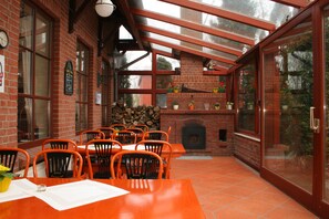 A brick-walled room with a fireplace, wooden tables, and orange chairs. - Hotel Stettiner Hof (Neuenkirchen bei Greifswald)