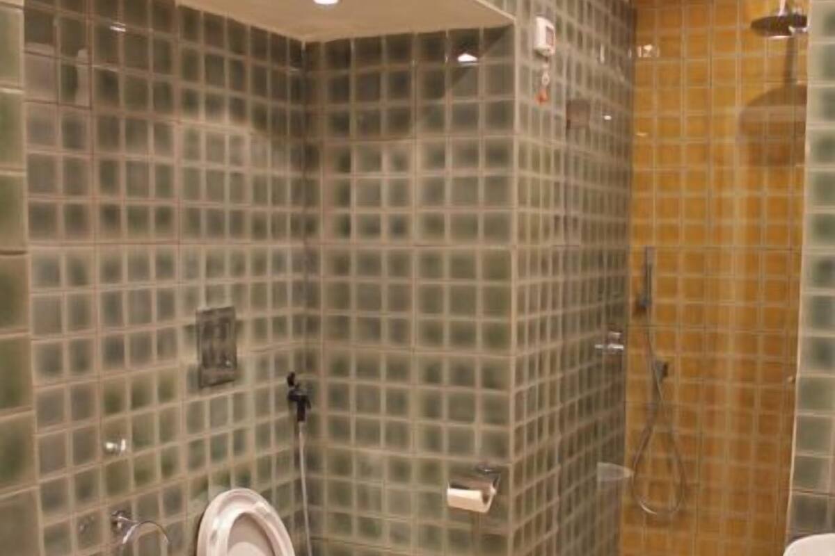 A bathroom with two toilets, a shower, and a sink.