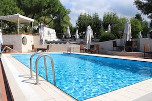 A swimming pool with lounge chairs and umbrellas, surrounded by trees. - Villa La Colombaia (Portici)