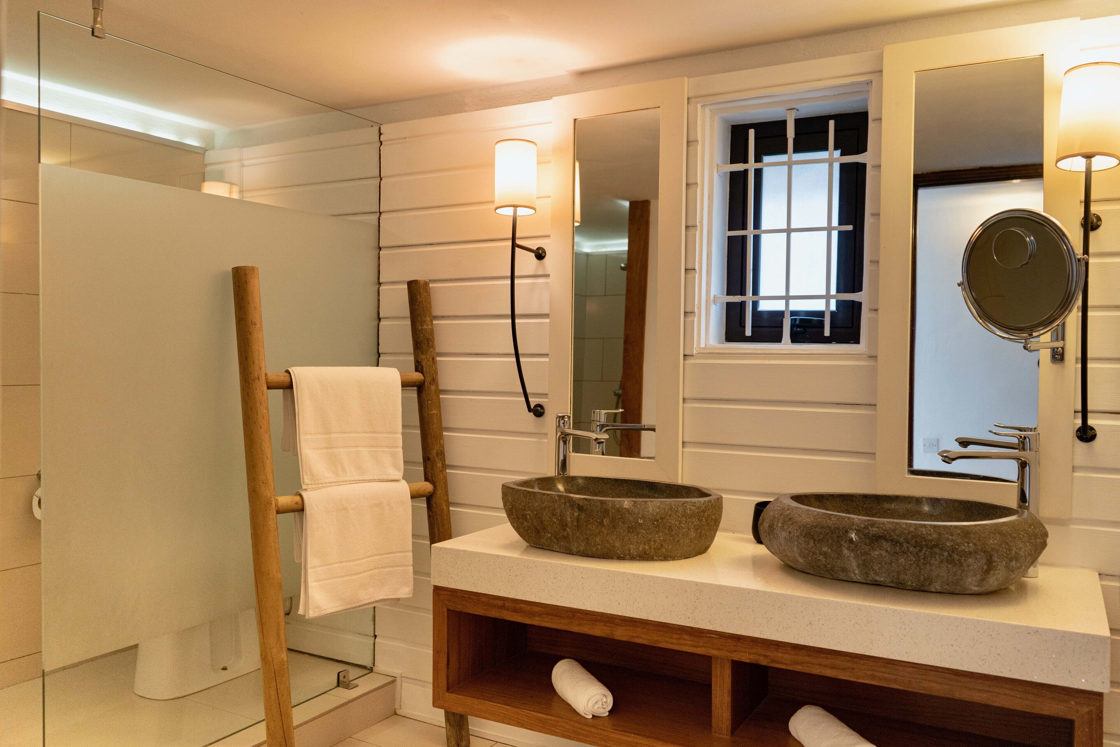 Une salle de bain avec un lavabo en pierre, un meuble-lavabo en bois et une cabine de douche en verre.