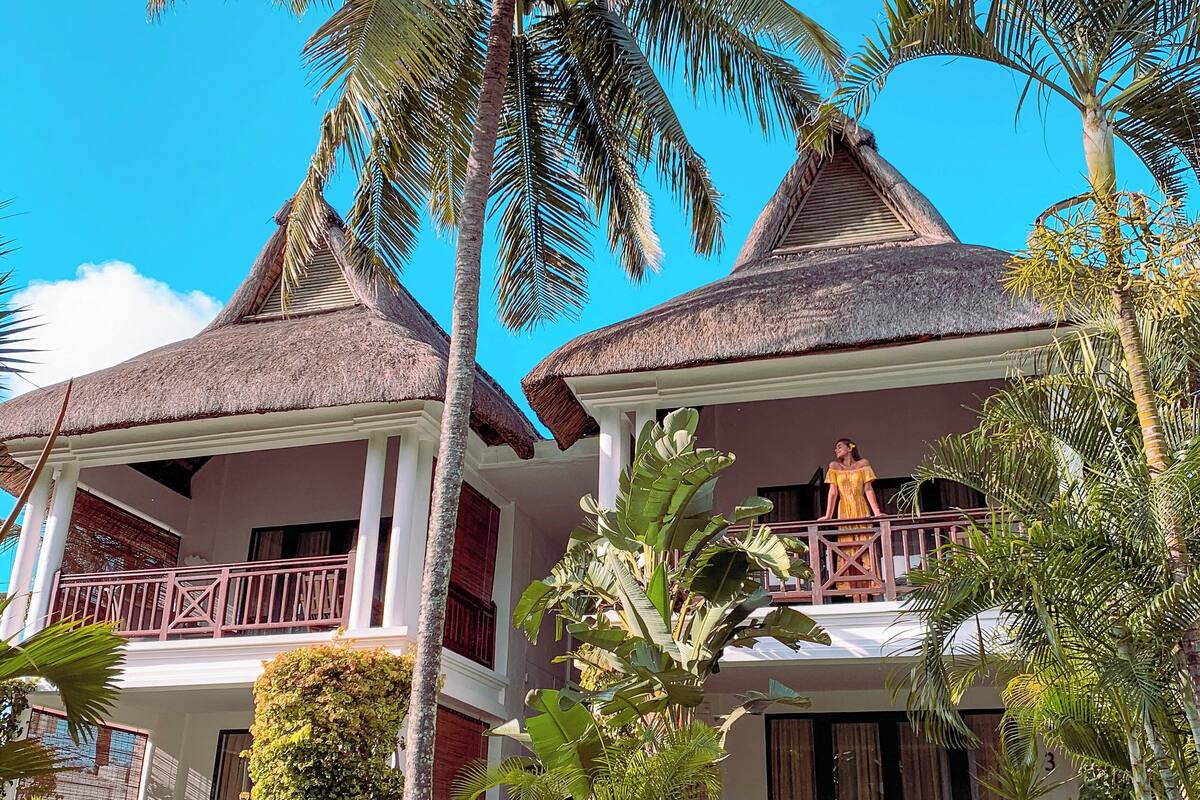 A resort with thatched-roof buildings, a well-maintained garden, and a statue.