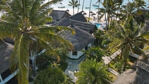 A resort with thatched-roof buildings, a pool, and a beach view. - Constance Sakoa Boutik (Trou aux Biches)