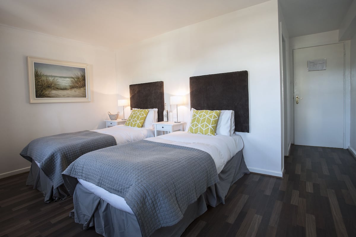 Una habitación de hotel con dos camas, un cuadro en la pared y una puerta.