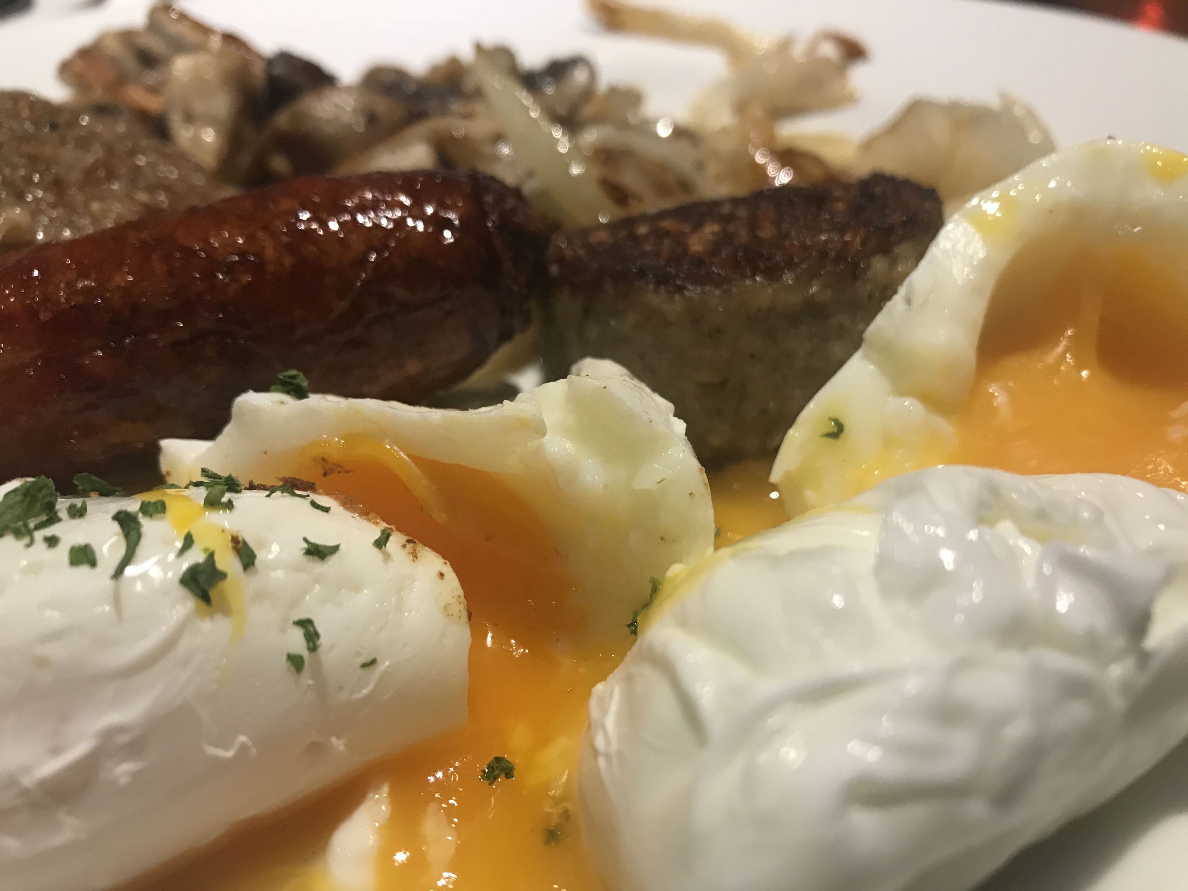 A breakfast plate with eggs, sausages, and hash browns.