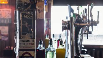 A bar with a tap and bottles on the counter.
