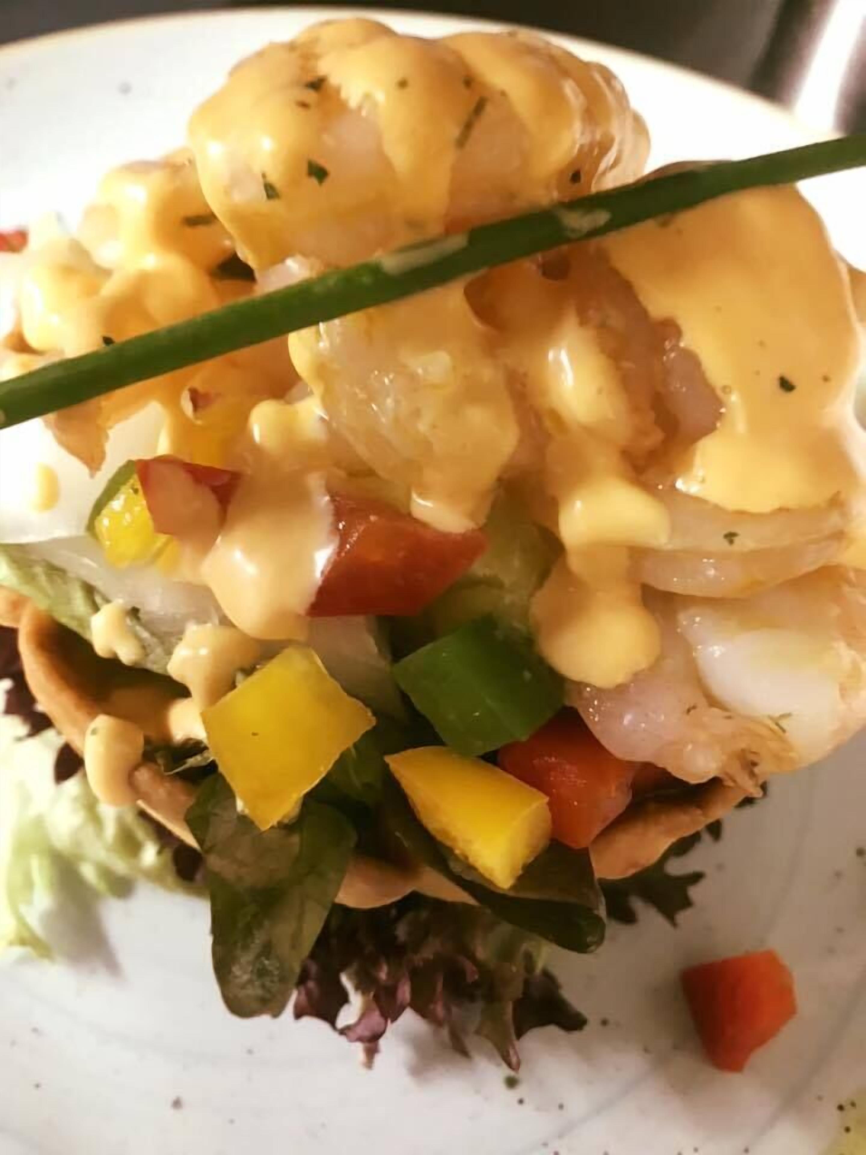 Un plat composé de crevettes, de légumes coupés en dés et nappé d’une sauce crémeuse.