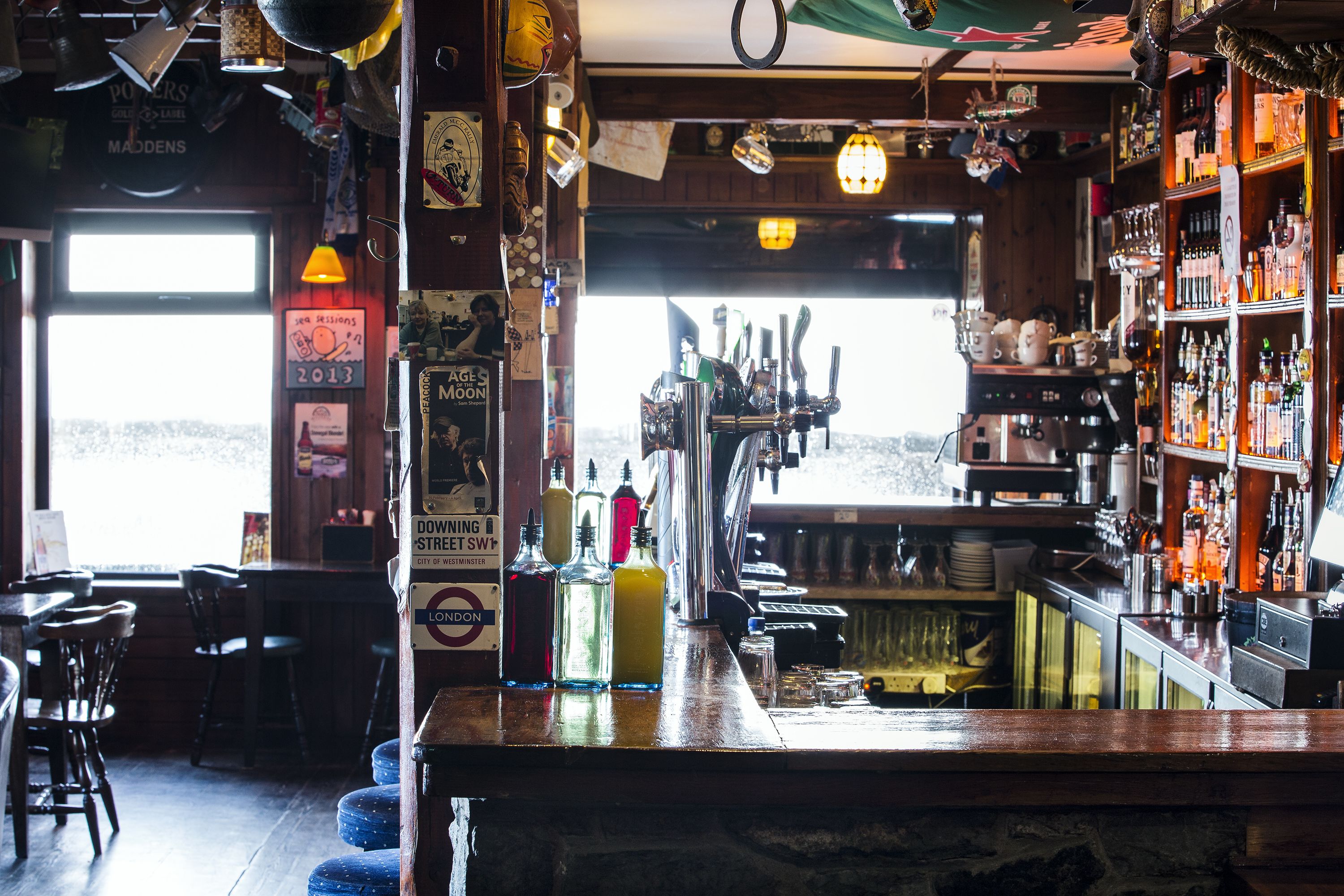 Un bar avec vue sur la mer, des meubles en bois et différentes bouteilles exposées sur des étagères.