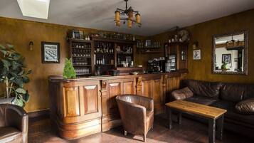 Una zona de bar con armarios de madera, un sofá de cuero y una mesa de madera.