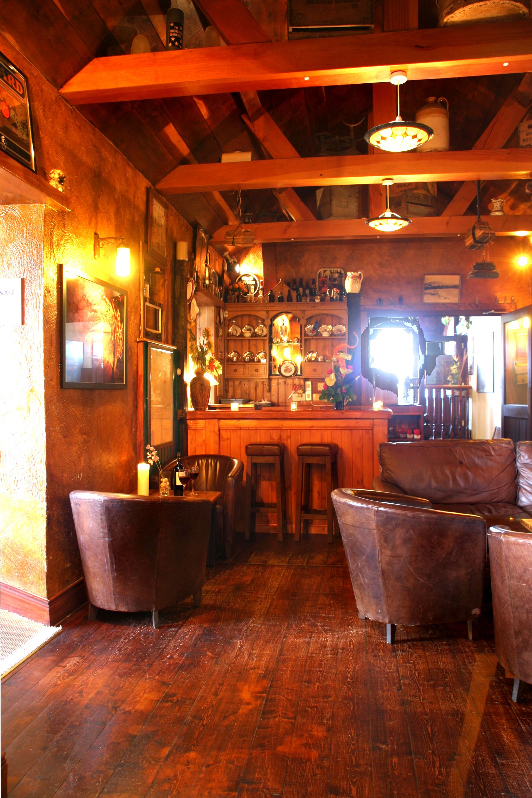 Un rincón de bar acogedor con vigas de madera, asientos de cuero y decoración rústica.