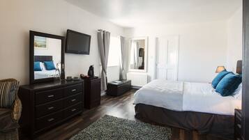 A bedroom with a bed, a dresser, a television, and a window with curtains.
