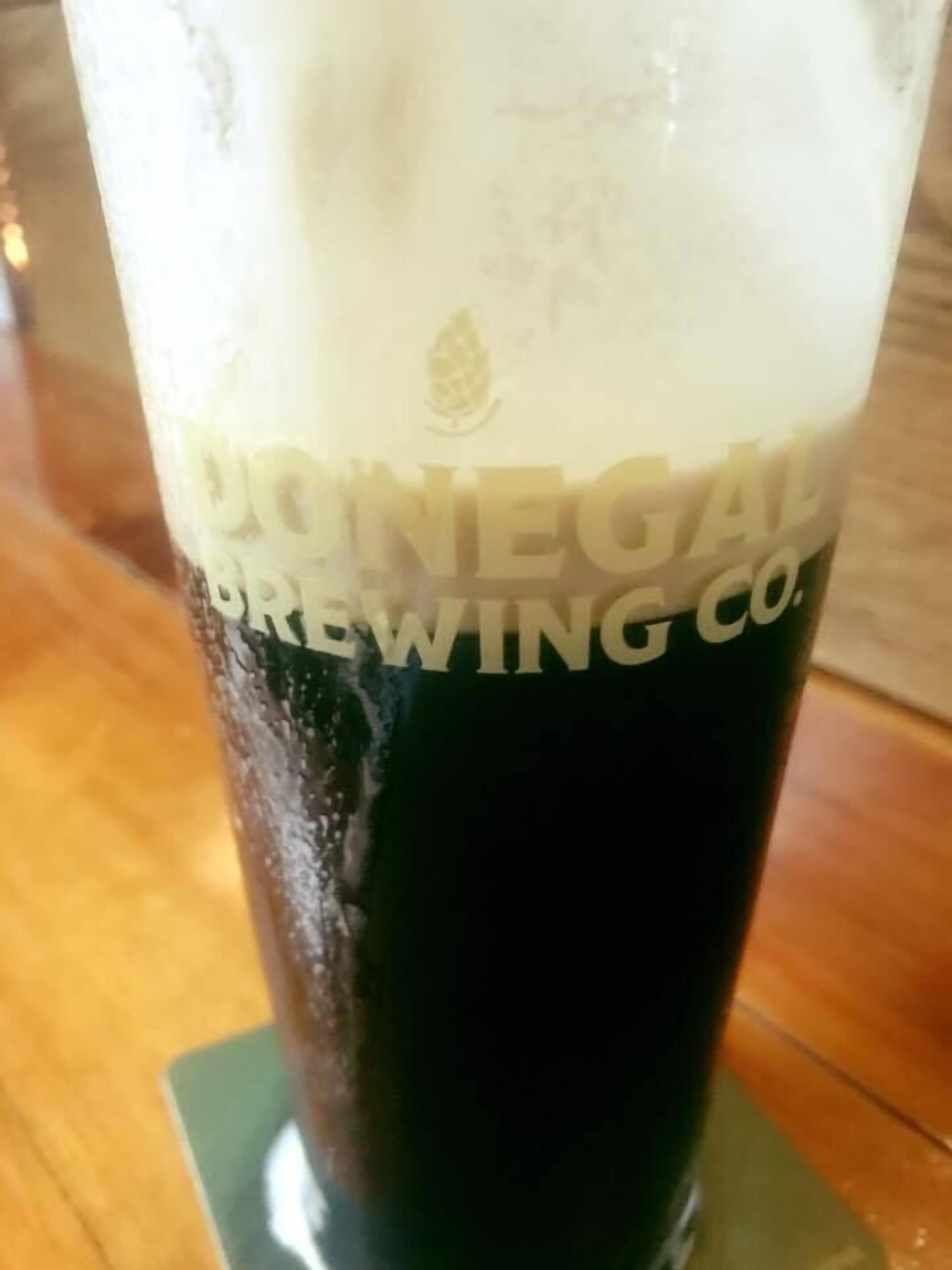 Un vaso de cerveza oscura con una espuma abundante, etiquetado como "DORNEGALE BREWING CO.".