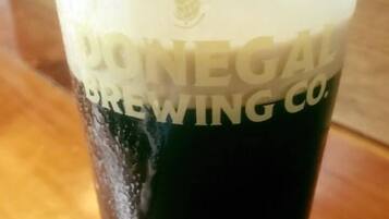 Un vaso de cerveza oscura con una espuma abundante, etiquetado como "DORNEGALE BREWING CO.".