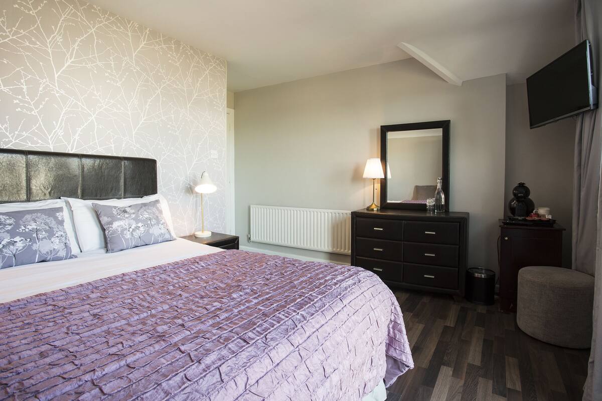 Un dormitorio con cama, cómoda y televisor montado en la pared.