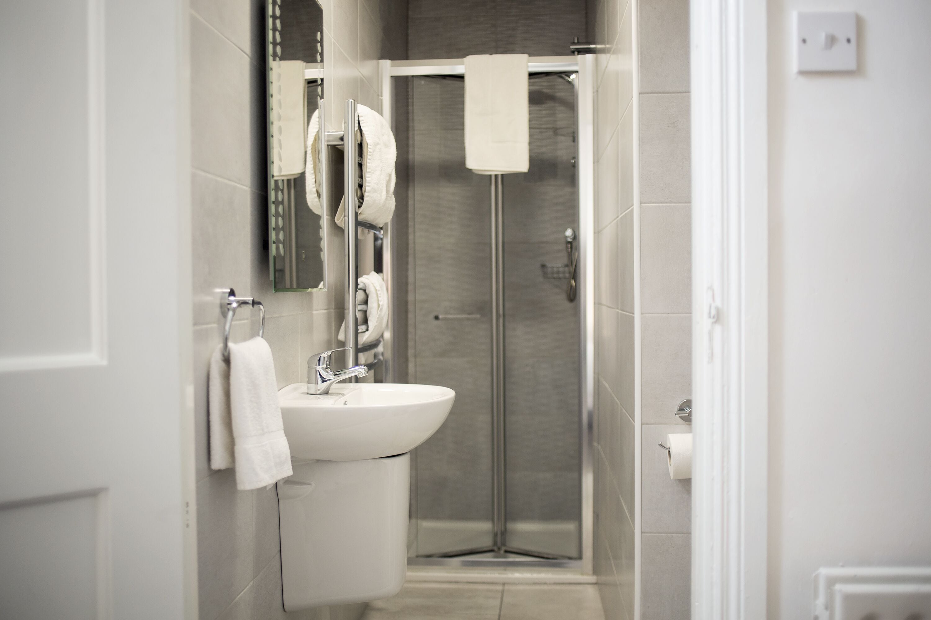 A modern bathroom with a sink, mirror, and shower.