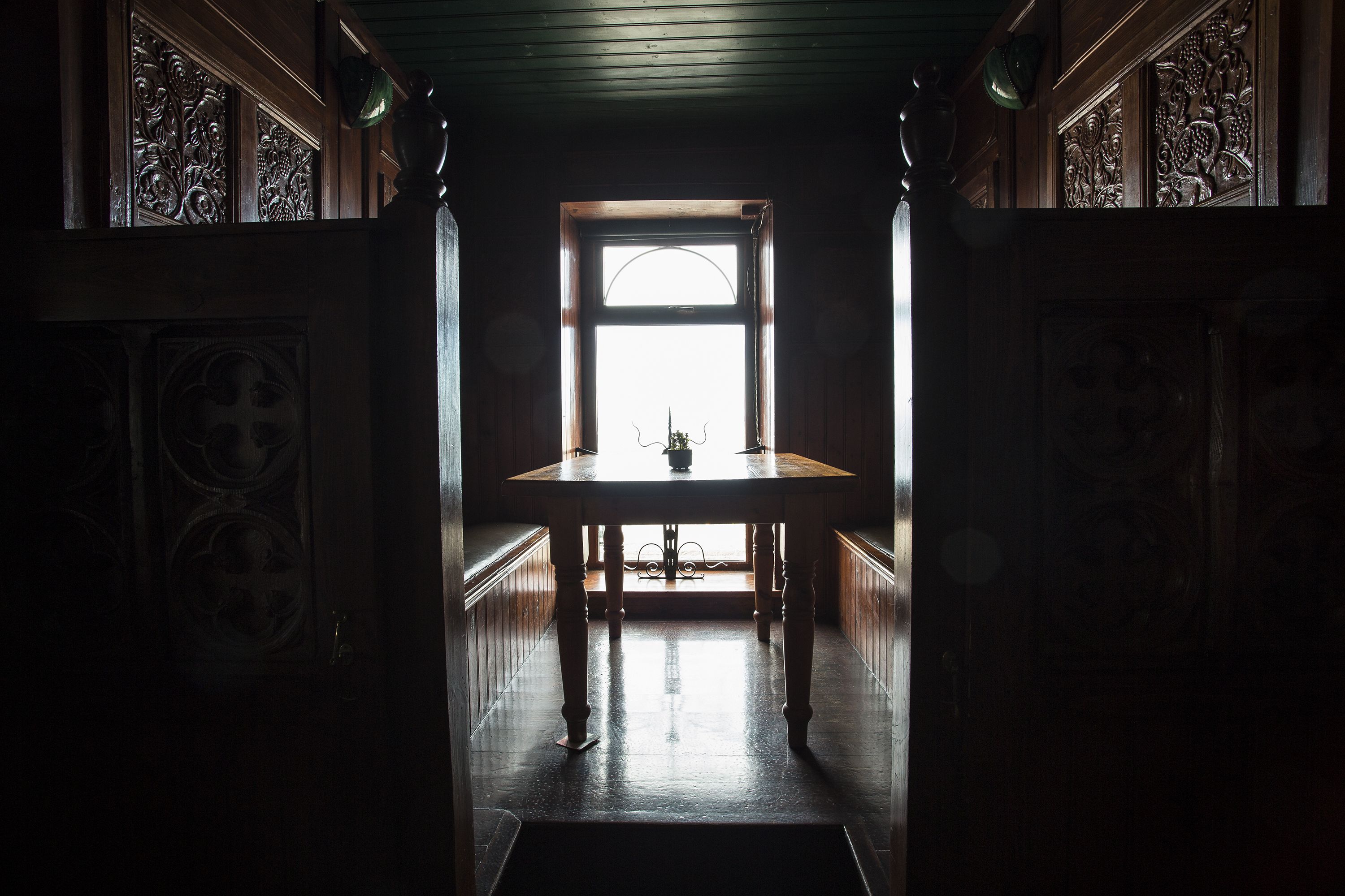A narrow hallway with a wooden table and a window at the end.