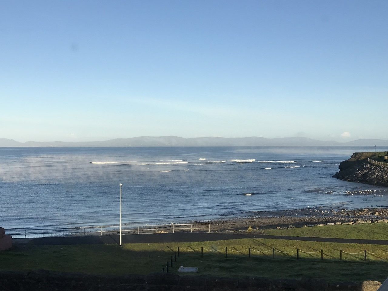 Une vue sur la côte, avec un phare, une côte rocheuse et des zones herbeuses.