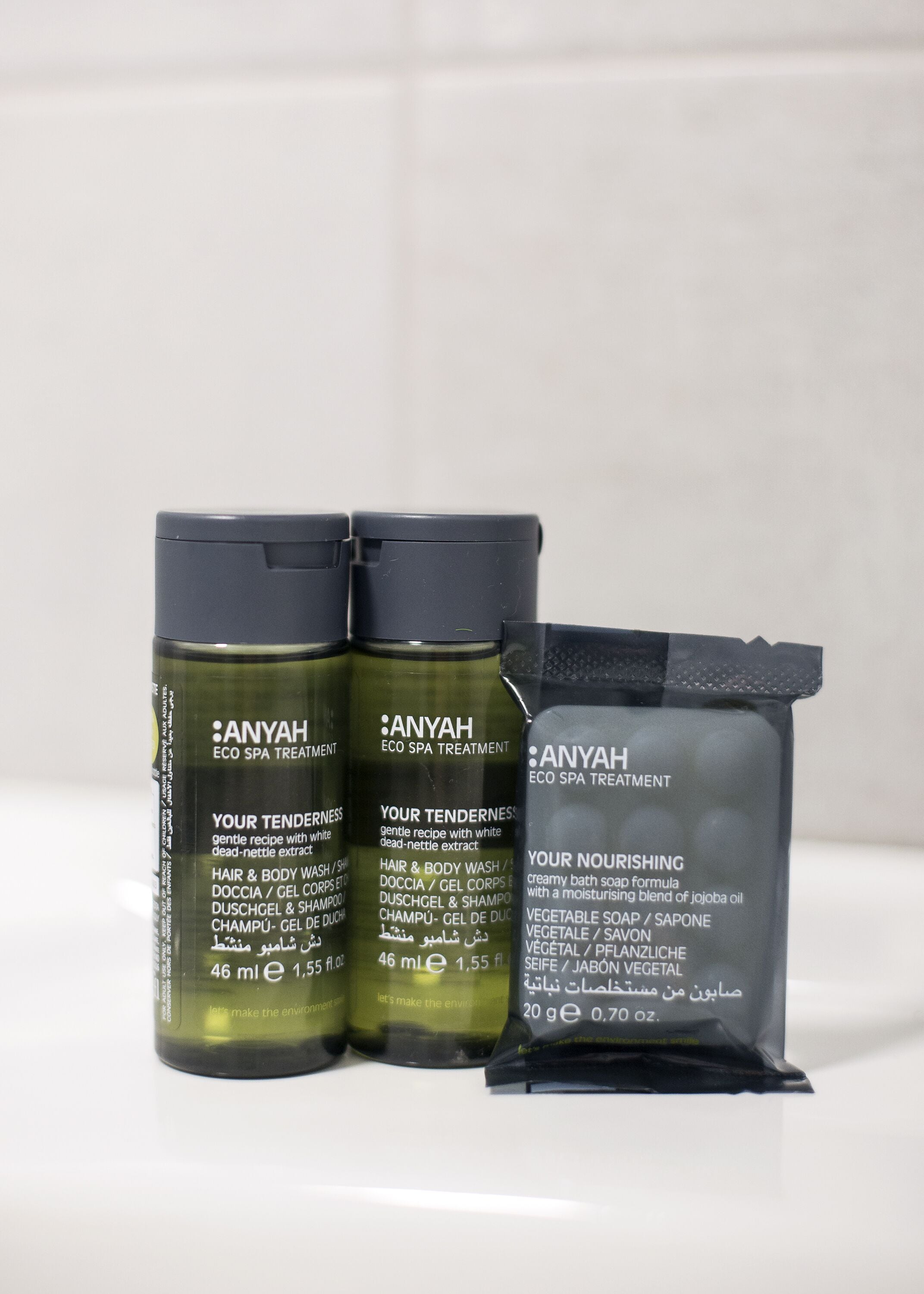 Tres botellas de productos de tratamiento ecológico Anyah y una pastilla de jabón de baño.