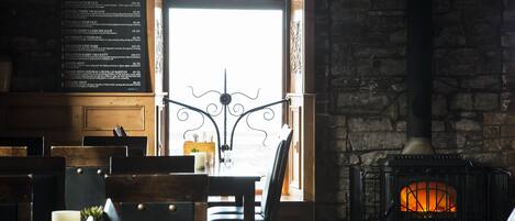 A cozy interior with a stone wall, a fireplace, and a menu board.