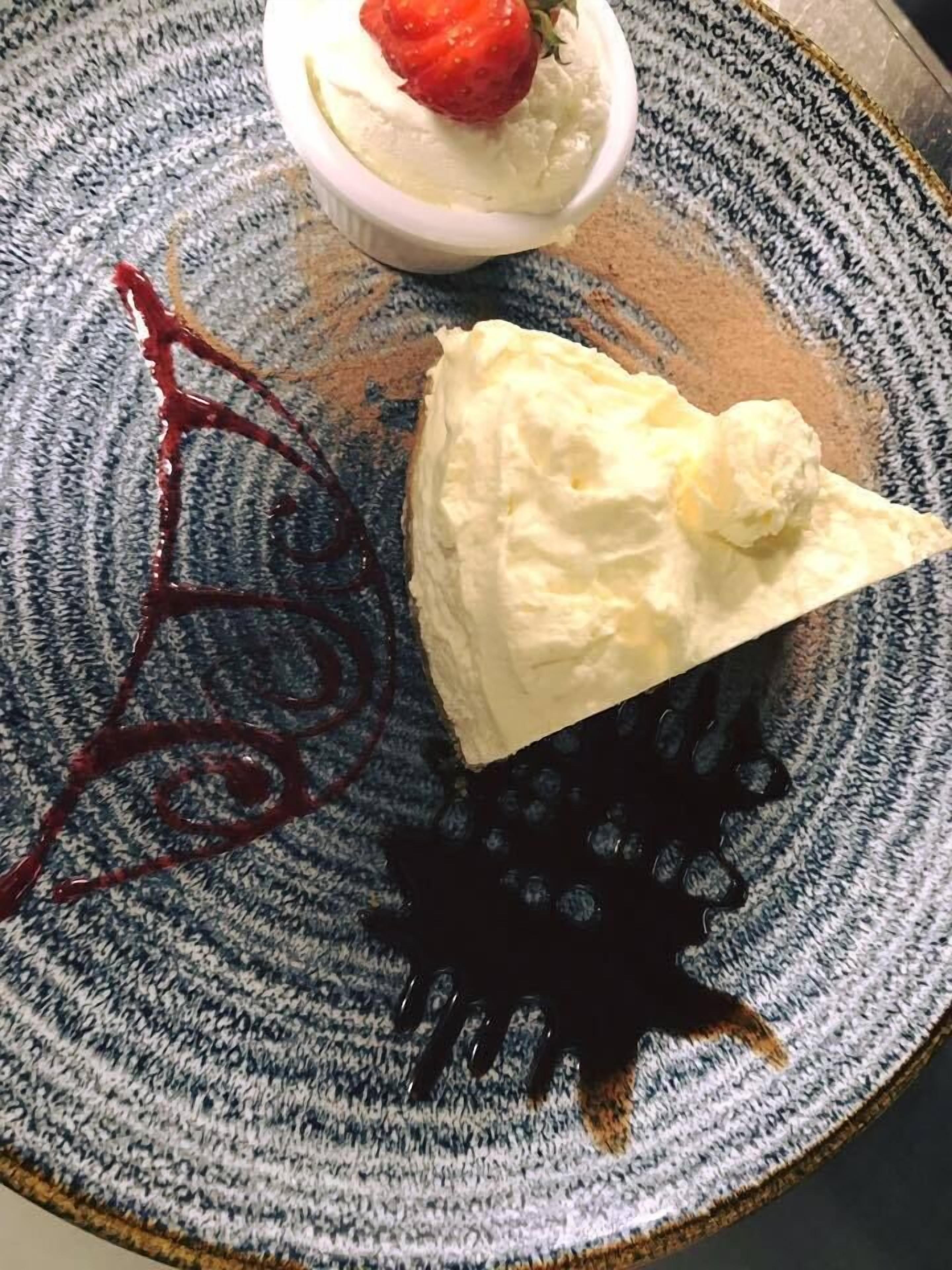 A dessert with a strawberry on top, a scoop of ice cream, and chocolate sauce on a plate.