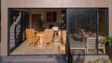 Un interior moderno con una puerta de vidrio que da a una sala de estar con muebles de mimbre, un sofá y una mesa de centro.
