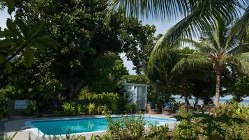 Una piscina circondata da vegetazione rigogliosa e vista sulla spiaggia.